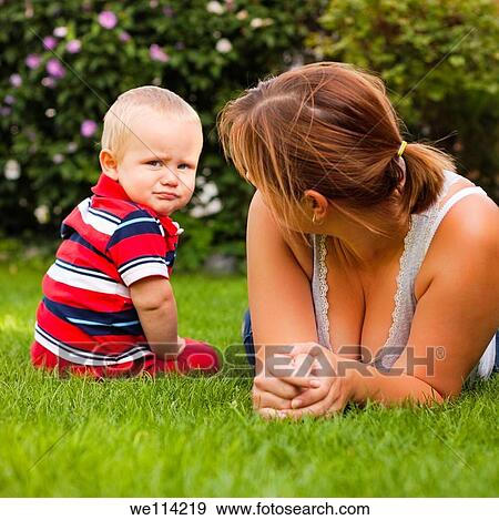 Stock Photo - Funny moment of offended toddler and his mother in the garden. Fotosearch