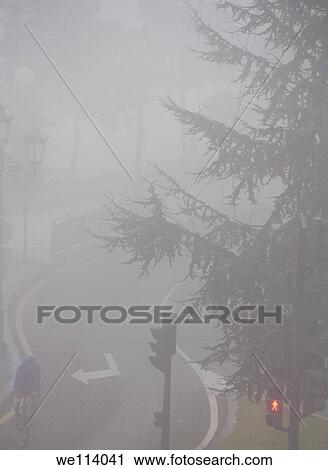 Man cycling on a city under the fog in the morning View Large Photo Image Stock Image - Man cycling on a city under the fog in the morning. Fotosearch