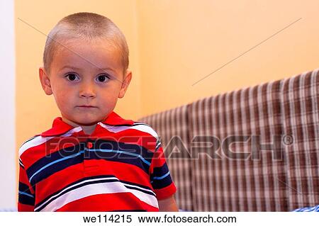 Stock Photography - Portrait of little boy sitting on the bed. Fotosearch