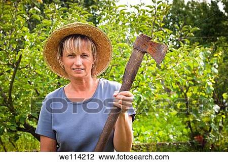 Stock Image - Portrait of mature woman holding axe in the garden. Fotosearch