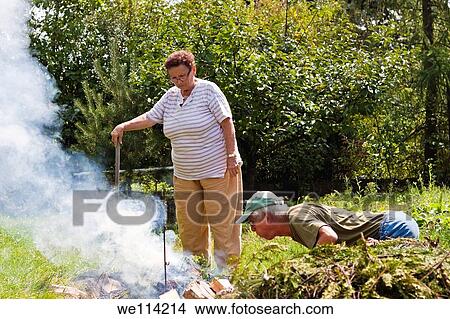 Senior couple trying to make a bonfire in the garden View Large Photo Image Picture - Senior couple trying to make a bonfire in the garden. Fotosearch