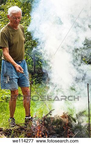 Senior man and bonfire in the garden View Large Photo Image Stock Photo - Senior man and bonfire in the garden. Fotosearch