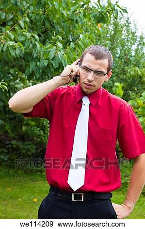 Stock Photo - Serious young Caucasian businessman with green natural background. Fotosearch