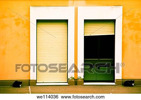 Stock Photograph - Two cats sitting at the entance of a house. Fotosearch