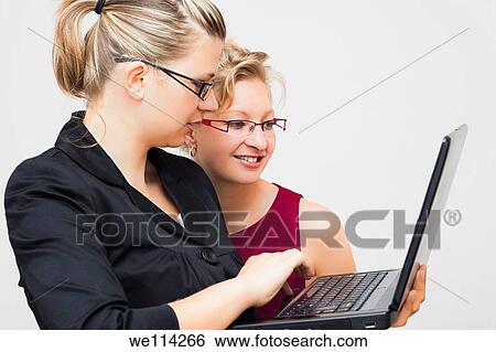 Stock Photograph - Two young business women with laptop. Fotosearch