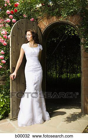 Stock Image - A young modern bride standing at the doorway. Fotosearch