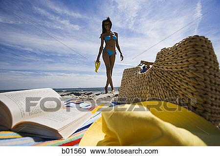 Beach towel with book and bag with a young woman in background View Large Photo Image Stock Image - Beach towel with book and bag with a young woman in background. Fotosearch