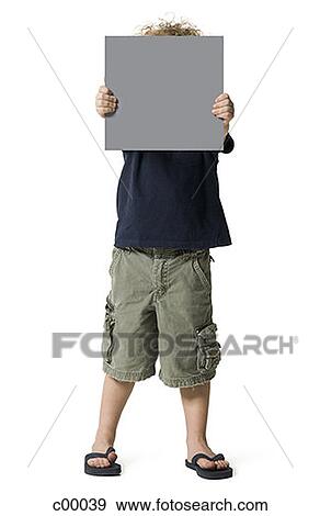 Boy holding a blank sign in front of his face View Large Photo Image Stock Photo - Boy holding a blank sign in front of his face. Fotosearch