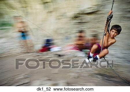 Stock Image - Boy swinging from a rope. Fotosearch