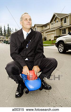 Stock Photography - Businessman driving a toy car. Fotosearch