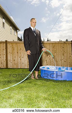 Businessman filling a wading pool with water View Large Photo Image Stock Photograph - Businessman filling a wading pool with water. Fotosearch