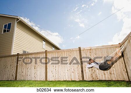 Businessman lying down in a hammock, talking on a mobile phone View Large Photo Image Picture - Businessman lying down in a hammock, talking on a mobile phone. Fotosearch