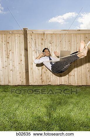 Businessman lying down in a hammock, talking on a mobile phone View Large Photo Image Stock Photography - Businessman lying down in a hammock, talking on a mobile phone. Fotosearch