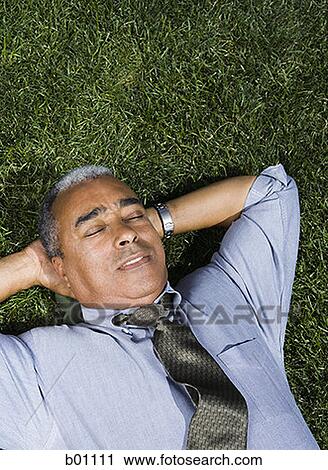 Businessman lying on a lawn View Large Photo Image Stock Image - Businessman lying on a lawn. Fotosearch