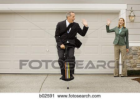 Businessman on a pogo stick waving at a businesswoman View Large Photo Image Stock Image - Businessman on a pogo stick waving at a businesswoman. Fotosearch