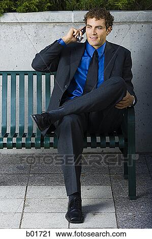 Businessman sitting on a bench, talking on a mobile phone View Large Photo Image Stock Image - Businessman sitting on a bench, talking on a mobile phone. Fotosearch