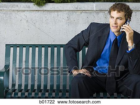 Businessman sitting on a bench, talking on a mobile phone View Large Photo Image Stock Image - Businessman sitting on a bench, talking on a mobile phone. Fotosearch