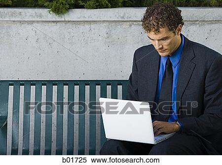 Stock Photography - Businessman sitting on a bench, using a laptop. Fotosearch