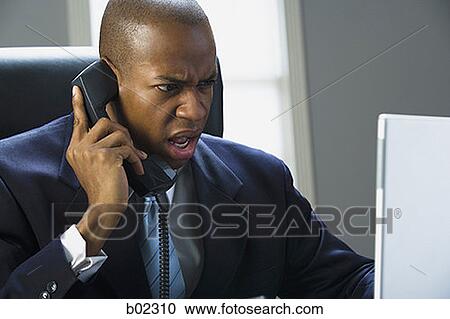 Businessman working on a laptop computer and talking on the phone View Large Photo Image Stock Image - Businessman working on a laptop computer and talking on the phone. Fotosearch