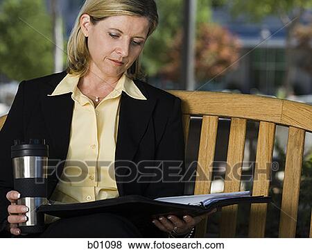 Businesswoman sitting on a bench with a file View Large Photo Image Stock Photo - Businesswoman sitting on a bench with a file. Fotosearch