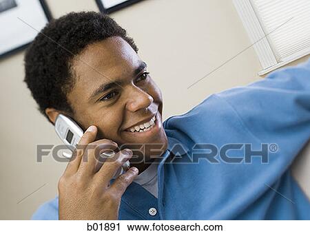 Close-up of a boy talking on a mobile phone smiling View Large Photo Image Stock Image - Close-up of a boy talking on a mobile phone smiling. Fotosearch