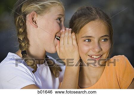 Close-up of a girl whispering into her friend's ear View Large Photo Image Stock Photograph - Close-up of a girl whispering into her friend's ear. Fotosearch