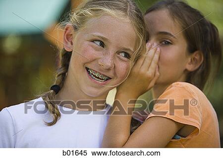 Close-up of a girl whispering into her friend's ear View Large Photo Image Stock Photography - Close-up of a girl whispering into her friend's ear. Fotosearch