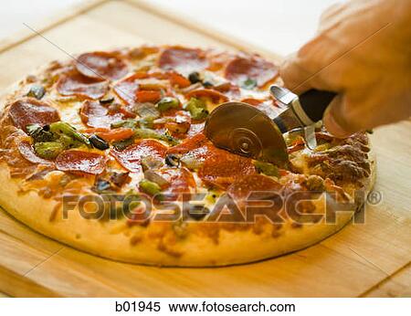 Close-up of a hand cutting a pizza with a pizza cutter View Large Photo Image Stock Photography - Close-up of a hand cutting a pizza with a pizza cutter. Fotosearch