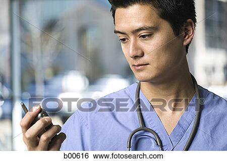 Close-up of a male doctor holding a mobile phone View Large Photo Image Stock Photograph - Close-up of a male doctor holding a mobile phone. Fotosearch