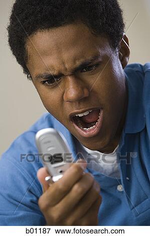 Close-up of a teenage boy shouting at a mobile phone View Large Photo Image Stock Photo - Close-up of a teenage boy shouting at a mobile phone. Fotosearch