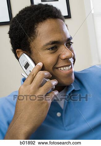 Close-up of a teenage boy talking on a mobile phone and smiling View Large Photo Image Stock Image - Close-up of a teenage boy talking on a mobile phone and smiling. Fotosearch