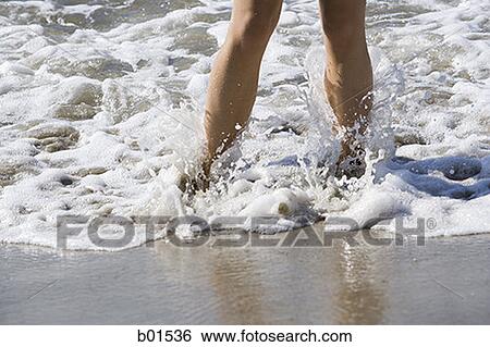 Close-up of a woman's legs in the surf View Large Photo Image Stock Photograph - Close-up of a woman's legs in the surf. Fotosearch