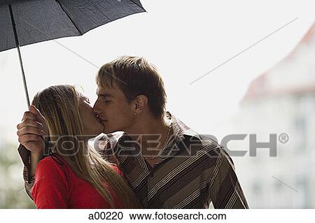 Close-up of a young couple kissing under an umbrella View Large Photo Image Stock Image - Close-up of a young couple kissing under an umbrella. Fotosearch