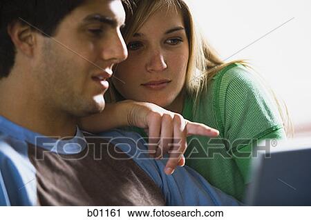 Close-up of a young couple looking at a laptop View Large Photo Image Stock Image - Close-up of a young couple looking at a laptop. Fotosearch