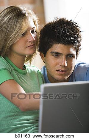 Close-up of a young couple looking at a laptop View Large Photo Image Stock Image - Close-up of a young couple looking at a laptop. Fotosearch