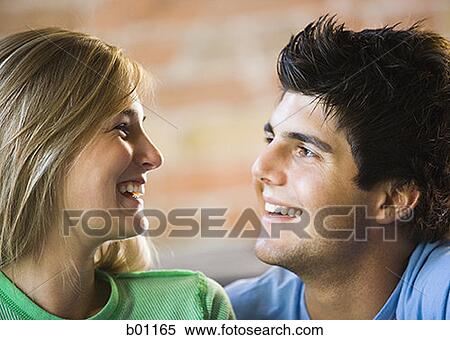 Close-up of a young couple looking at each other and smiling View Large Photo Image Stock Photography - Close-up of a young couple looking at each other and smiling. Fotosearch