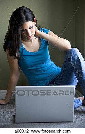 Stock Image - Close-up of a young Latin woman sitting in front of a laptop. Fotosearch