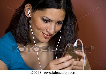 Close-up of a young Latin woman wearing headphones and listening to music View Large Photo Image Stock Photo - Close-up of a young Latin woman wearing headphones and listening to music. Fotosearch
