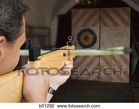 Close-up of a young man aiming at a target View Large Photo Image Stock Image - Close-up of a young man aiming at a target. Fotosearch
