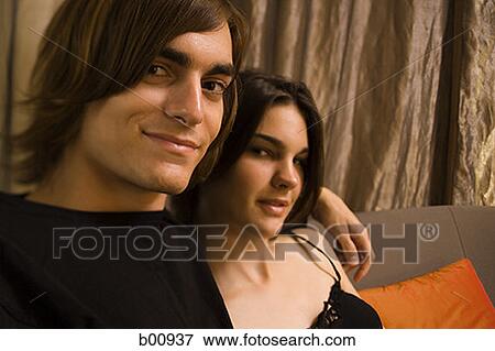 Close-up of a young man and a young woman sitting on a couch View Large Photo Image Stock Photo - Close-up of a young man and a young woman sitting on a couch. Fotosearch