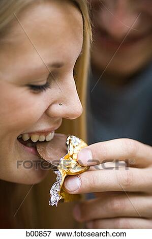 Close-up of a young man feeding a young woman a piece of chocolate View Large Photo Image Stock Photo - Close-up of a young man feeding a young woman a piece of chocolate. Fotosearch