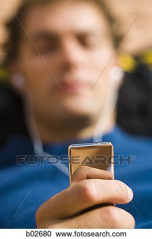 Close-up of a young man holding an MP3 Player View Large Photo Image Stock Image - Close-up of a young man holding an MP3 Player. Fotosearch