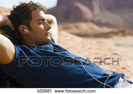 Close-up of a young man lying on his back and listening to an MP3 Player View Large Photo Image Stock Image - Close-up of a young man lying on his back and listening to an MP3 Player. Fotosearch