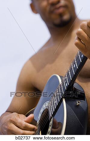 Close-up of a young man playing a guitar View Large Photo Image Stock Photo - Close-up of a young man playing a guitar. Fotosearch