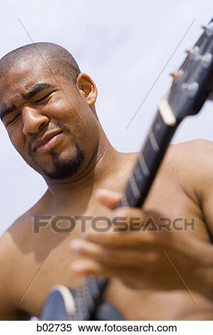 Close-up of a young man playing a guitar View Large Photo Image Stock Photography - Close-up of a young man playing a guitar. Fotosearch