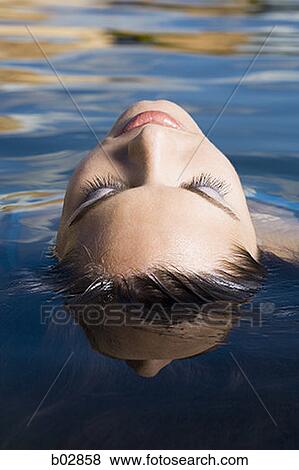 Close-up of a young woman floating on the surface of a lake View Large Photo Image Stock Photo - Close-up of a young woman floating on the surface of a lake. Fotosearch
