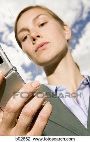 Close-up of a young woman holding a mobile phone View Large Photo Image Stock Image - Close-up of a young woman holding a mobile phone. Fotosearch