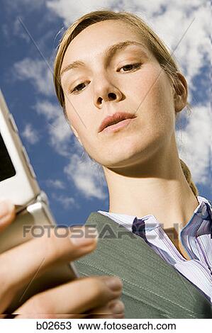 Close-up of a young woman holding a mobile phone View Large Photo Image Stock Image - Close-up of a young woman holding a mobile phone. Fotosearch