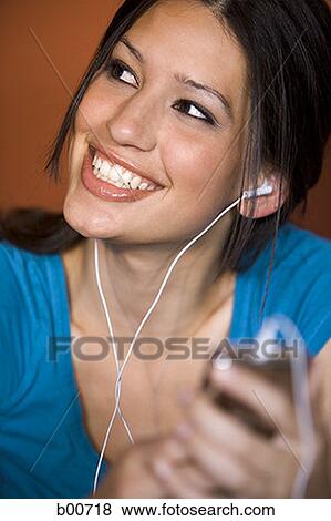 Close-up of a young woman listening to music View Large Photo Image Stock Photo - Close-up of a young woman listening to music. Fotosearch