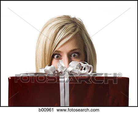 Close-up of a young woman looking at a gift View Large Photo Image Stock Image - Close-up of a young woman looking at a gift. Fotosearch